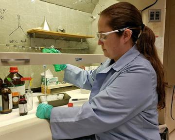 A postdoctoral research associate makes lures under a hood in the lab