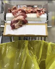 Meat rubs across the continuous sampling device (CSD) cloth into collection bin.