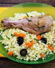 A plate containing a chicken leg and couscous.