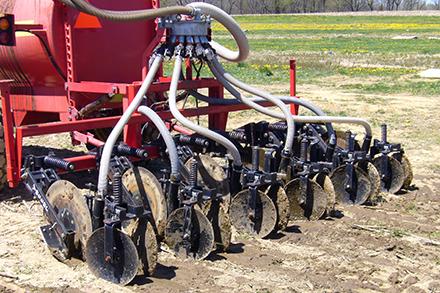 A tractor using a shallow disk tool to place manure into the soil.