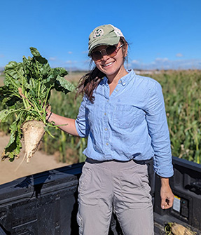 Elizabeth Hada holding a sugarbeet while standing in a sugarbeet field 