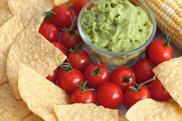 Tortilla chips, tomatoes, guacamole, and corn.