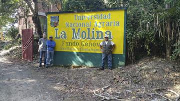 Three scientists standing in front of a sign for a research station in Peru