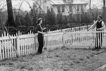 historical photo of two people talking over a fence