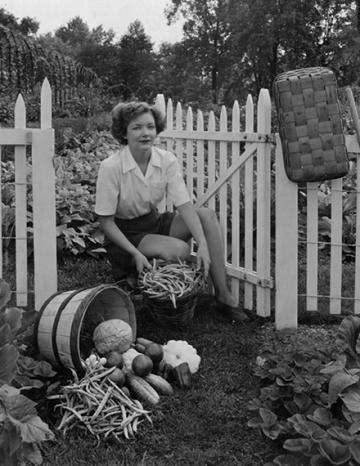 historical photo of a woman with baskets of harvested vegetables