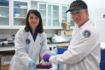 In a NASA lab, Fatma Kaplan holds a tray while David Shapiro-Ilan loads glass tubes into it