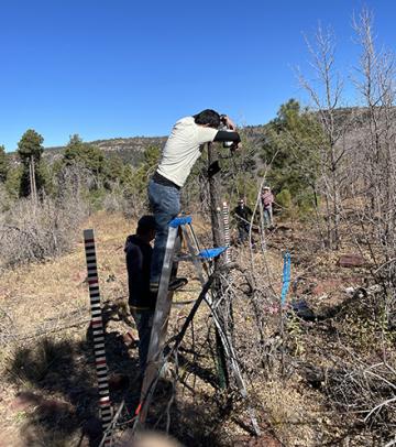 Dr. Ravindra Dwivedi aiming a trail camera to capture several graduated snowtography stakes.