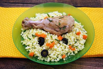A plate containing a chicken leg and couscous.