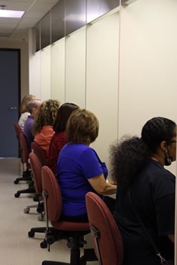 Six people sitting in front of sensory booths.