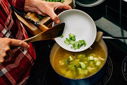 Broccoli stems being added to a pot of soup.