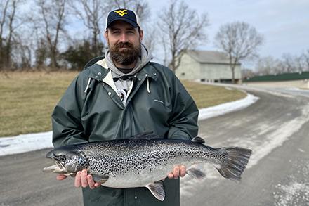 Travis May standing outside holding an Atlantic salmon.