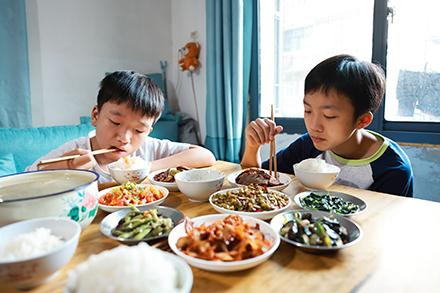 Two Chinese boys eating a traditional meal. 