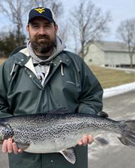 Travis May standing outside holding an Atlantic salmon.