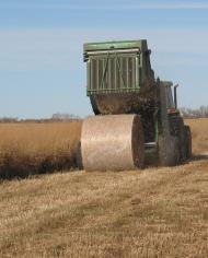 A machine rolls hay into round bales in a field